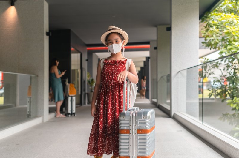 Chinese tourist wearing a facial mask in an airport, happy to go on a journey as vaccinations are continuing